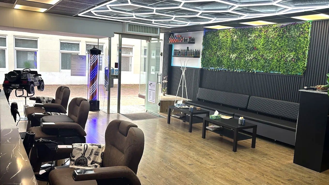 De salon met stoelen links, het hexagon-plafondlicht en de plantenwand rechts